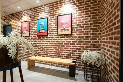 a brick wall with posters on it with a bench at M-Stay Hostel in Chemor