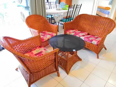 a group of wicker chairs and a table with a tableablish at Affordable Cozy Apartment @ Coral Bay Resort in Pasir Bogak