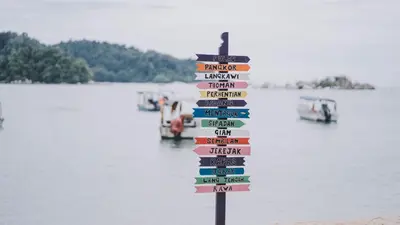 a sign on the beach with boats in the water at Affordable Cozy Apartment @ Coral Bay Resort in Pasir Bogak