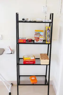 a black shelf with books and other items on it at monstera homestay (Lenggong) in Kampong Ulu Jepai