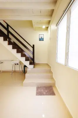 a staircase in a house with a table and a window at monstera homestay (Lenggong) in Kampong Ulu Jepai
