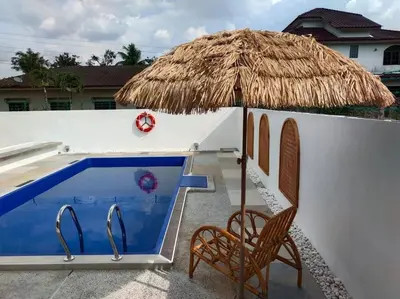a straw umbrella and chairs next to a swimming pool at Bole Villa-Private Pool-BBQ-Karaoke 20pax in Ipoh