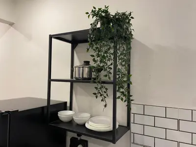 a black shelf with plates and plants on it at Dudu Guesthouse Ipoh in Ipoh