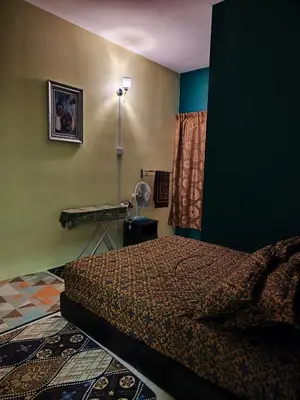 a bedroom with a bed and a table with a fan at Nanalacy Homestay ISLAM SAHAJA in Tanah Rata