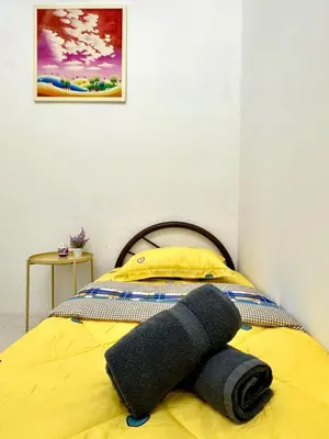 a yellow bed with a gray towel on it at Casa Ipoh Homestay by Comfort Home in Chemor