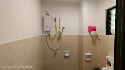 a bathroom with a shower with a yellow hose at 3 Rooms Apartment - Near Beach in Kampong Sungai Udang