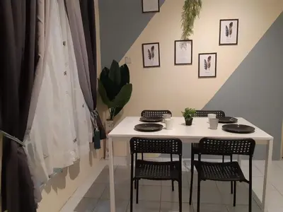 a table with four chairs and a white table with plates and cups at Ammar Homestay Gua Musang in Gua Musang