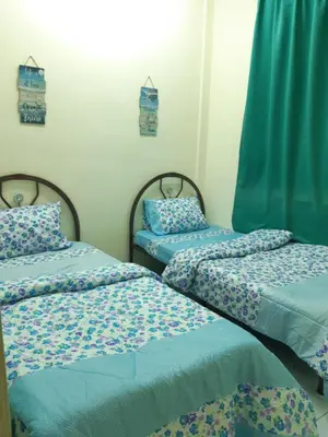 two twin beds in a room with blue sheets at Ammar Homestay Gua Musang in Gua Musang