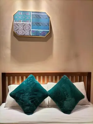two green pillows on a bed with a picture on the wall at Le Meilleur in George Town