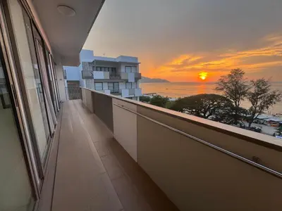 a balcony of a building with a sunset in the background at By The Sea with Direct Seaview level7 in Batu Ferringhi
