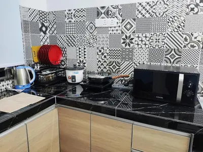 a kitchen with a black counter top with a microwave at A One Holiday Apartment - PRO in Tanah Rata