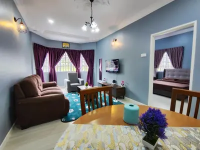 a living room with a couch a table and a bedroom at A One Holiday Apartment - PRO in Tanah Rata