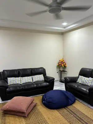 a living room with a couch and a pillow on the floor at Homestay Hajrah in Ipoh