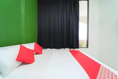 a bedroom with red and white pillows and a black curtain at Hotel O My Budget Home in Batu Ferringhi