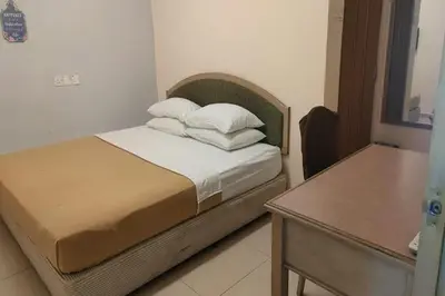 a bedroom with a bed with white pillows and a table at F Hotel Bayan Lepas in Bayan Lepas