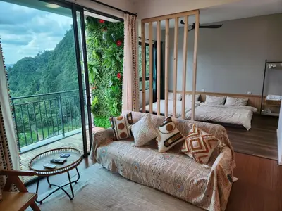 a living room with a couch and a balcony at Unique Boho Style Condo with NETFLIX for up to 5PAX - Enjoy Mountain View while swimming at the Infinity Pool & Natural Hotspring Pool, 2mins walk to the Lost World of Tambun, Water Themepark at IPOH in Ipoh