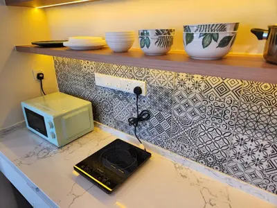a kitchen counter with a microwave and bowls on a shelf at Unique Boho Style Condo with NETFLIX for up to 5PAX - Enjoy Mountain View while swimming at the Infinity Pool & Natural Hotspring Pool, 2mins walk to the Lost World of Tambun, Water Themepark at IPOH in Ipoh