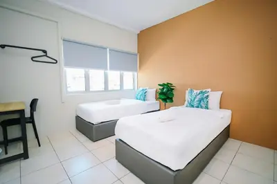 a bedroom with two beds and a desk in it at Swing & Pillows - Penang Road, Georgetown Penang in George Town