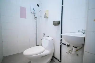 a white bathroom with a toilet and a sink at Swing & Pillows - Penang Road, Georgetown Penang in George Town