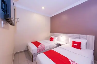 two beds in a hotel room with red pillows at Spring Inn Hotel in Sungai Petani