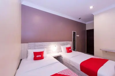 two beds in a hotel room with red pillows at Spring Inn Hotel in Sungai Petani