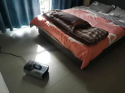 a video game system sitting on the floor next to a bed at WingsNest Cameron Town Night Market High Speed Wi-Fi in Tanah Rata