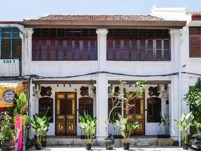 a white building with wooden doors and plants at Carnarvon Antique Loft in George Town