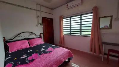 a bedroom with a bed with pink sheets and a window at SEROJA HOMESTAY in Baling