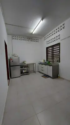 a large kitchen with white walls and a white floor at SEROJA HOMESTAY in Baling