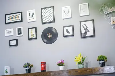 a white wall with framed pictures and plants on it at Jovial Modern Stylish Townhouse 8pax - BM Icon City in Bukit Mertajam