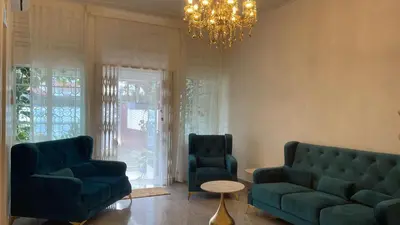 a living room with two blue couches and a chandelier at British Granny's Cottage in Georgetown in Jelutong