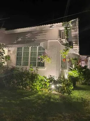 a white house with windows and plants in the yard at British Granny's Cottage in Georgetown in Jelutong