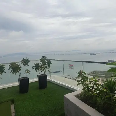 a balcony with two potted plants and the ocean at Urban Suites JSW GEORGETOWN PENANG, MALAYSIA in Jelutong