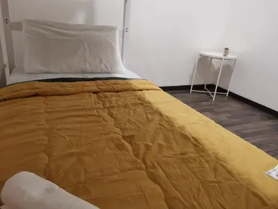 a bed with a yellow comforter and a table at G FORTUNE GUEST HOUSE+ in George Town