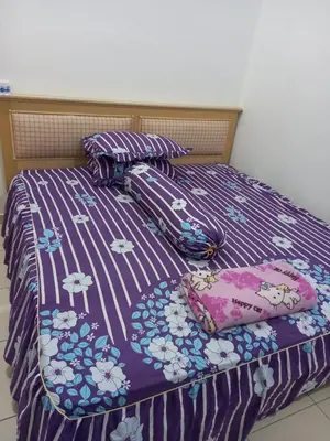 a bed with a purple comforter and pillows on it at D'tasek Homestay Gua Musang in Gua Musang
