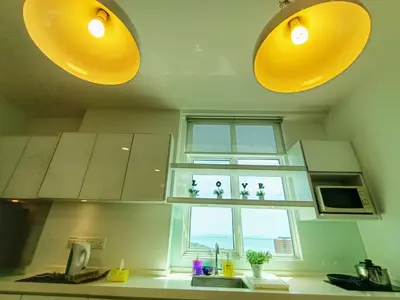a kitchen with yellow lights above a sink and a window at Deluxe suites 3, 1BR, 2-5 pax, Netflix, Georgetown in George Town