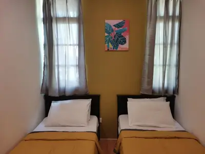 two beds in a room with two windows at G FORTUNE HOTEL + in George Town