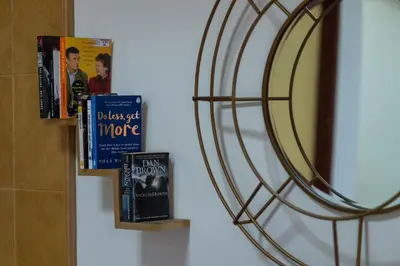 a shelf with books and a mirror on a wall at Jemhaus Studio Sunset Seaview [Netflix & Cuckoo] in Lumut