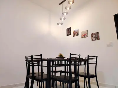 a dining room table with chairs and a ceiling light at Samudera Seri Manjung Residences by Manhattan Group in Kampong Pundut