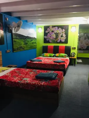two beds in a room with green and red at Lily Haven Hotel C-1 in Tanah Rata