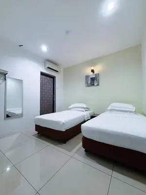 two beds in a room with white walls at Asia Green Hotel in Sungai Besar