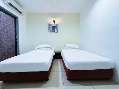 two twin beds in a room with a window at Asia Green Hotel in Sungai Besar