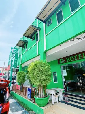 a green hotel with a tree in front of it at Asia Green Hotel in Sungai Besar