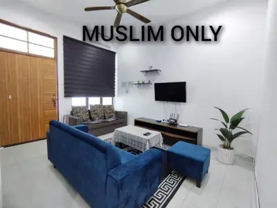 a living room with a blue couch and a tv at Indah Damai Homestay in Kepala Batas