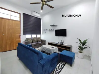 a living room with a blue couch and a tv at Indah Damai Homestay in Kepala Batas