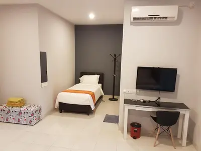 a bedroom with a bed and a desk with a television at White House Homestay in Ipoh