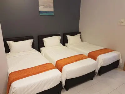 three beds in a room with white and orange sheets at White House Homestay in Ipoh