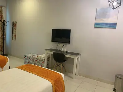 a bedroom with a bed and a desk with a television at White House Homestay in Ipoh