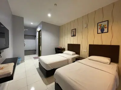 a hotel room with two beds and a flat screen tv at M Three Hotel in Kampong Batu Tiga