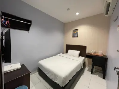 a small bedroom with a bed and a desk at M Three Hotel in Kampong Batu Tiga